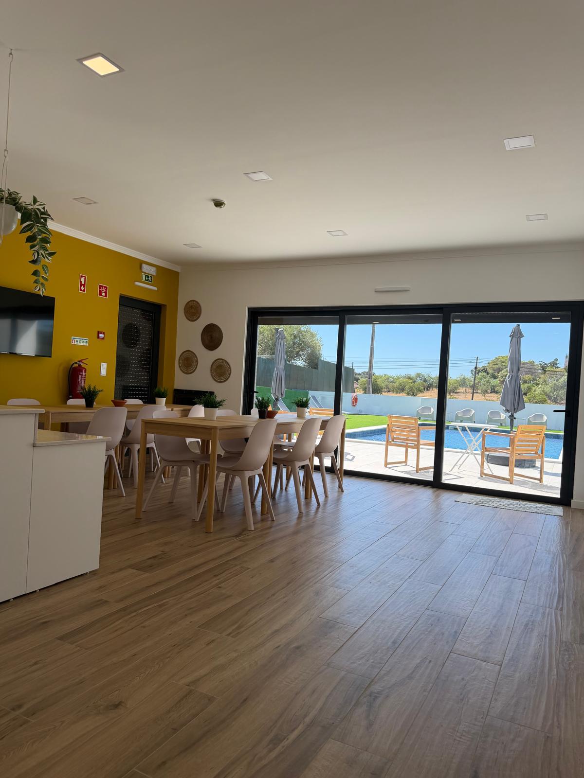 Sala comum com mesas de refeição e acesso direto à piscina